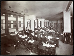 Hommes et une femme travaillant à des bureaux dans un bureau de la Metropolitan Life Insurance Co. à la 23ème Rue et Madison Avenue, New York, 1907